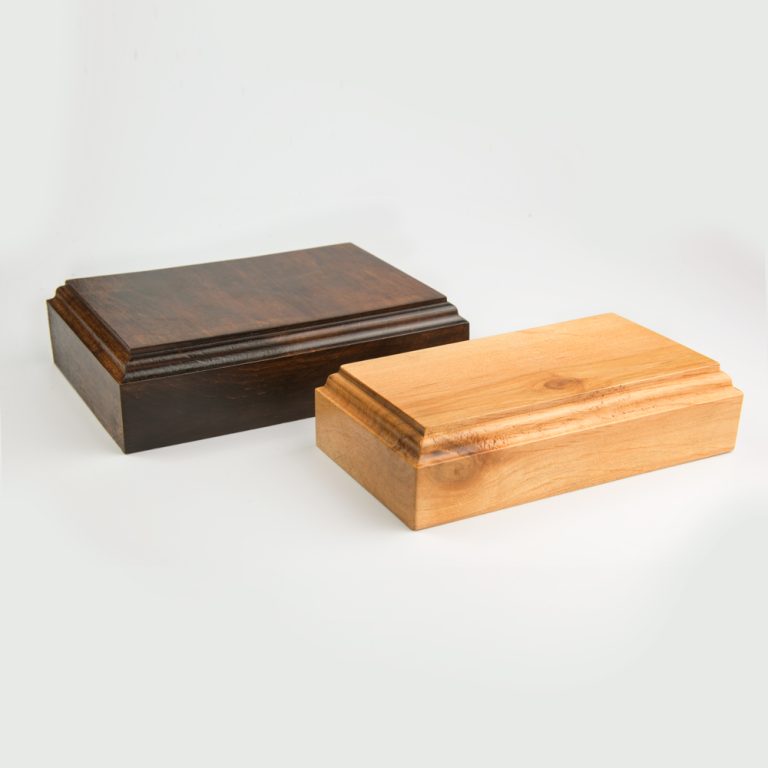 Zdjęcie dwóch podstawek drewnianych o klasycznym frezie ustawionych równolegle względem siebie. Podstawki mają wysokość czterech centymetrów. Podstawka z lewej strony jest ciemnobrązowa, a podstawka od prawej jasnobrązowa.